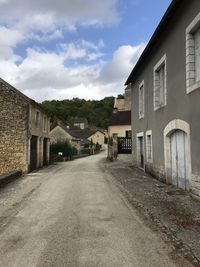 Empty road amidst buildings against sky