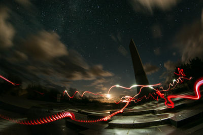 Low angle view of light trails against sky at night