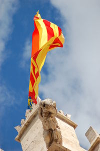 Low angle view of sculpture and flag against sky