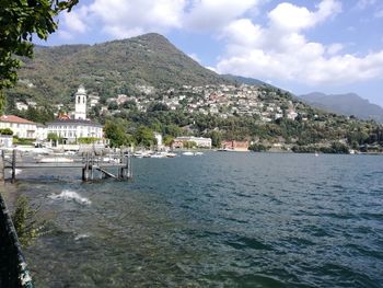 Scenic view of sea by townscape against sky