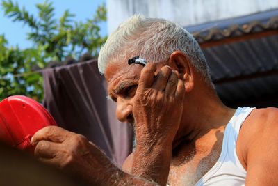 Low angle view of senior man using razor