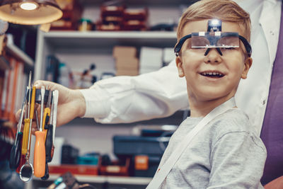 Happy kid with magnifying eyeglasses during physics experiment in engineering lab.