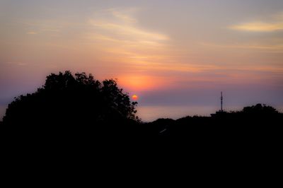 Silhouette trees against scenic sky