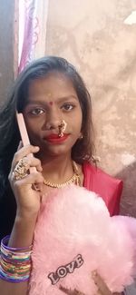 Portrait of beautiful woman standing against pink wall