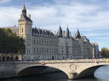 Arch bridge over river against sky in city