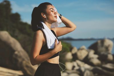 Side view of young woman looking away while standing at beach