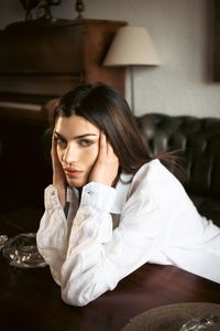Young woman sitting on bed at home