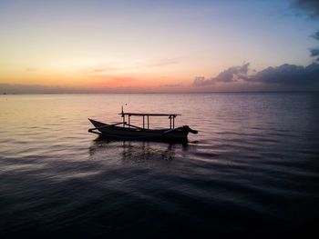 Boat moored in sea against sky during sunset