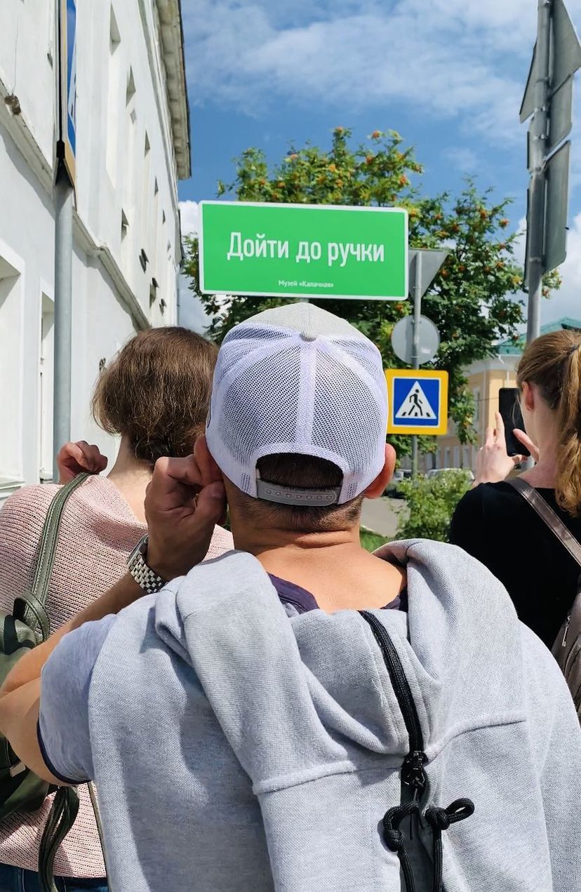 REAR VIEW OF PEOPLE WITH TEXT ON STREET AGAINST BUILDINGS