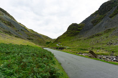 Road amidst green mountains against sky