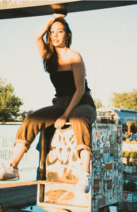 Portrait of young woman sitting on railing