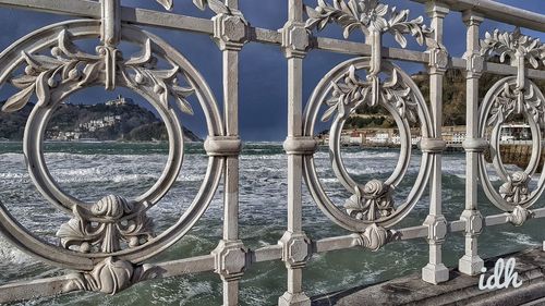 Close-up of metal railing by sea