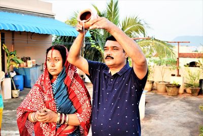 Mature couple praying while standing on terrace