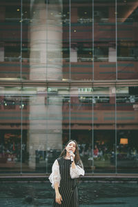 Full length of woman standing against glass wall