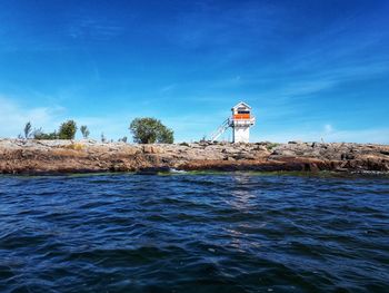 Lighthouse by sea against sky