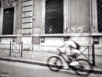 Blurred motion of bicycle on street against building