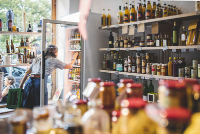 Female employee arranging bottles in refrigerator at deli