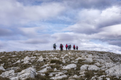 People on snow covered land against sky