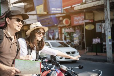 Young couple standing hitchhiking in city