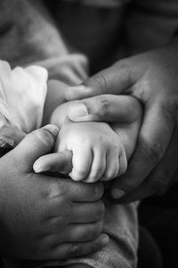 Cropped image of parents holding baby hand