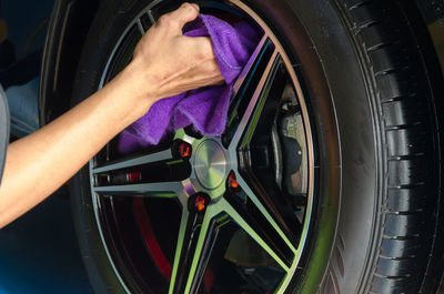 Cropped image of mechanic cleaning wheel in garage