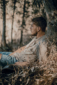 Side view of young man looking away in forest