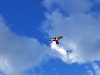 Low angle view of kites flying against blue sky