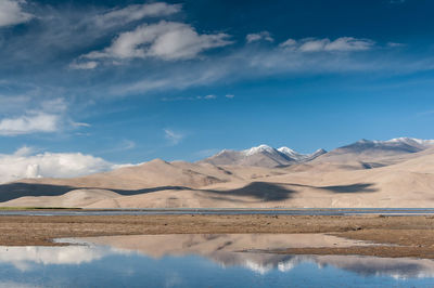 Scenic view of lake by mountains against sky