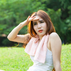 Woman shielding eyes while sitting on field