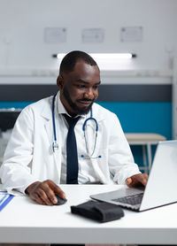 Doctor using laptop while sitting at hospital