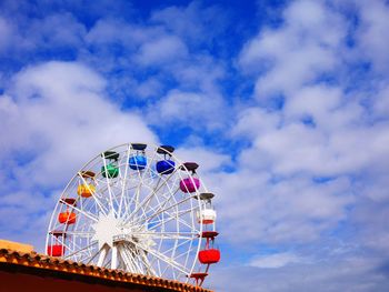 Low angle view of ferris wheel against the clouds