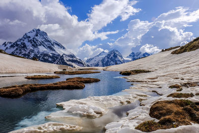 Scenic view of lake and snowcapped mountains against cloudy sky