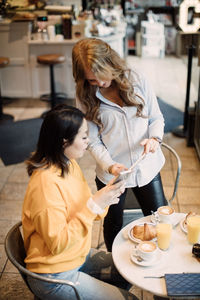 Multi-ethnic female photographers sharing smart phone at cafe