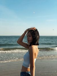 Woman standing at beach against sky