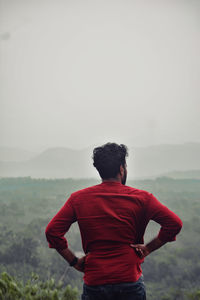 Rear view of man standing on mountain against sky