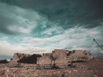 Abandoned building against cloudy sky