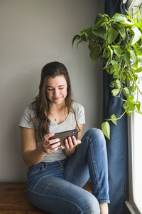 Smiling portrait of individual woman on her phone at home