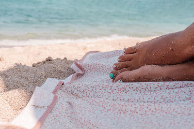 High angle view of woman hand on sand at beach