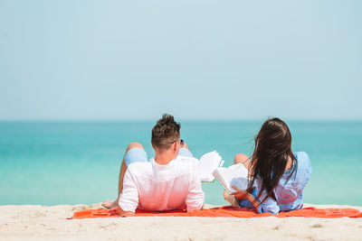 People sitting on beach by sea against sky