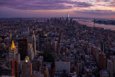 Aerial view of modern buildings against cloudy sky in city at dusk