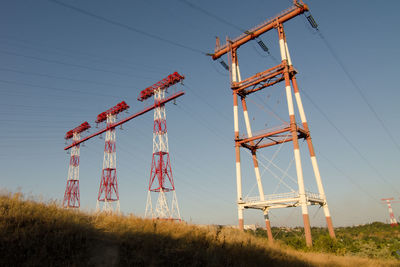 Low angle view of cranes on field against sky