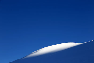 Low angle view of snow against clear blue sky