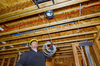 Low angle view of man working on ceiling