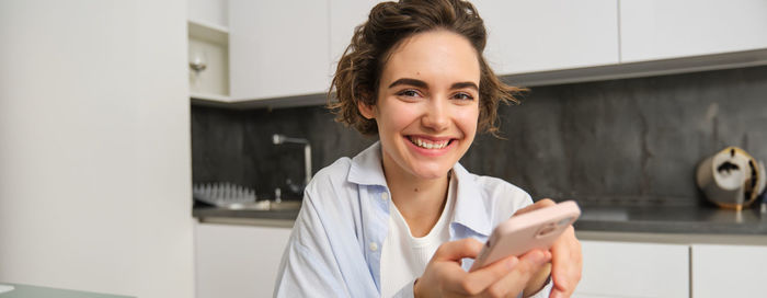 Portrait of young woman using mobile phone at home