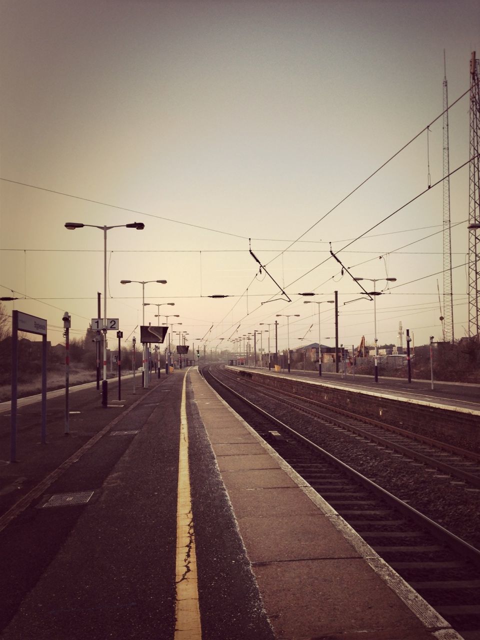 railroad track, transportation, rail transportation, the way forward, railroad station platform, diminishing perspective, railroad station, public transportation, clear sky, power line, vanishing point, electricity pylon, sky, connection, sunset, road marking, cable, empty, travel, railway track