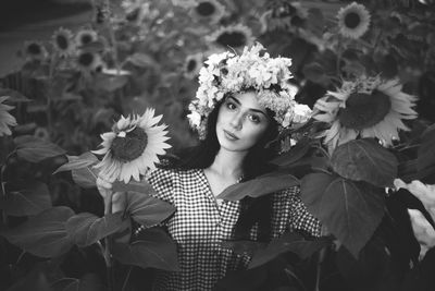 Portrait of young woman standing amidst sunflower field