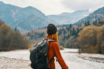 Rear view of woman looking at mountains against sky