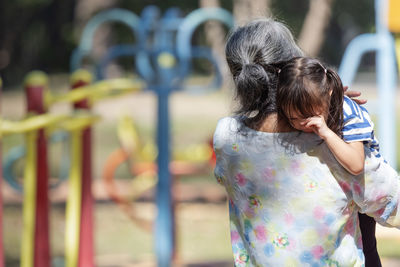 Rear view of mother holding daughter at playground