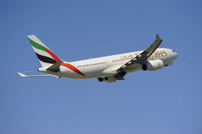 Low angle view of airplane flying against clear blue sky