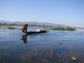 Man working in boat against sky